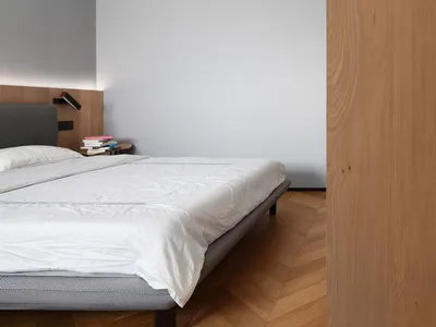A minimalist bedroom with wooden walls and a neatly made bed.