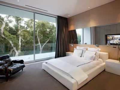 現代住宅臥室，採用木質與皮革質感家具，大型窗戶可眺望樹景，搭配俐落簡約設計
