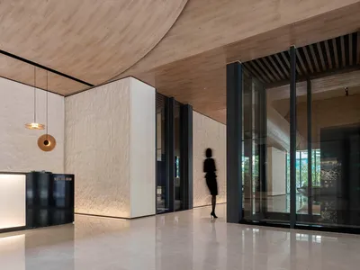 A modern hotel lobby featuring a wooden archway and marble flooring.