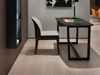 A modern industrial home office with a wooden desk and chair, a black and white abstract painting, and a built-in floating sh