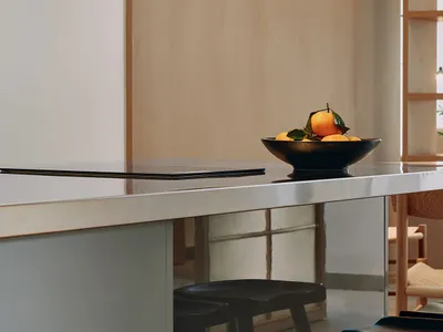 A sleek, modern kitchen counter made of metal with a bowl of oranges on top.