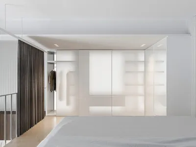 Modern minimalist bedroom featuring glass panel furniture and LED lighting under white ceiling and wooden floor.