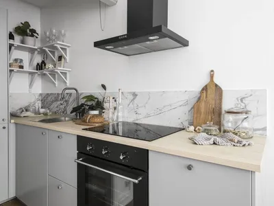 A minimalist kitchen with a wooden countertop and marble backsplash