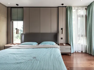 A contemporary minimalist bedroom with a grey leather headboard, blue bedding, and green curtains.