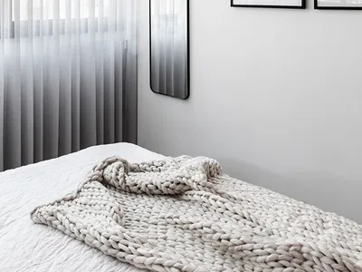 簡約臥室內有白色床鋪搭配紋理毯、框式藝術畫作，以及透光紗簾引入自然光線