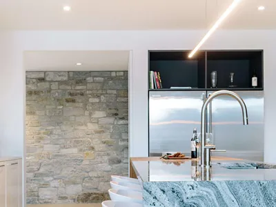 Modern minimalist kitchen featuring a sleek granite countertop and white stools.