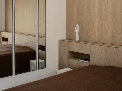 Minimalist bedroom featuring wooden vanity and mirrors.
