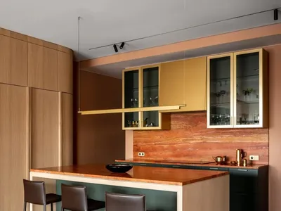 A modern kitchen featuring a wooden island with three bar stools, and cabinets with glass doors.