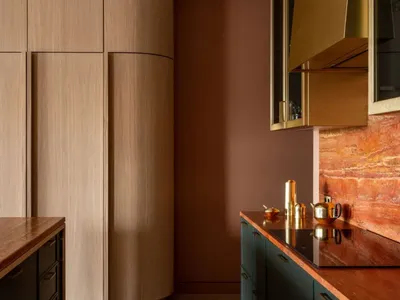 A modern kitchen with wooden cabinets, metallic accents, and a marble countertop.