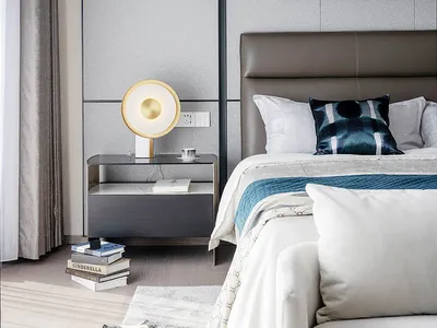 A modern bedroom featuring grey furnishings, a leather headboard, and a glass bedside table.