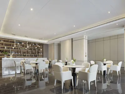 A modern restaurant interior featuring elegant white marble finishes and sleek white furniture.