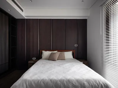 A minimalist bedroom with wooden paneling, white bedding, and two pillows.