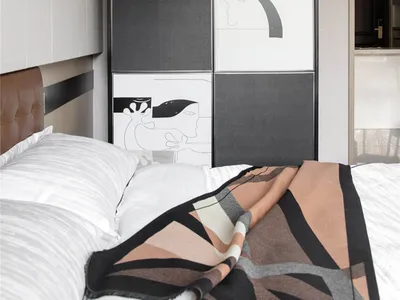 A modern bedroom featuring fabric bedding and abstract artwork.
