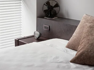 A minimalist bedroom with concrete furniture, a white bed, and brown pillows.
