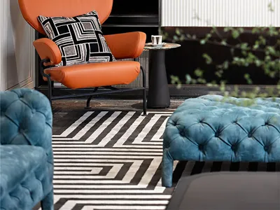Contemporary lounge area with fabric upholstered ottoman and leather chair.
