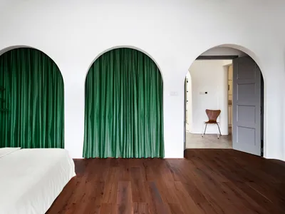 Modern bedroom with green curtains and wooden floor.