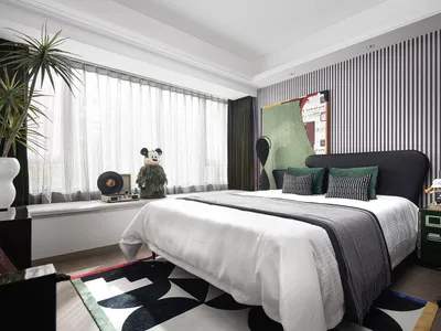 A modern bedroom interior with a white bed, green and black accents, and a striped wall.
