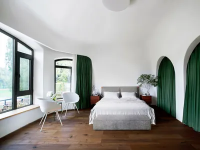 A modern bedroom with white furniture, green curtains, and a wood floor.