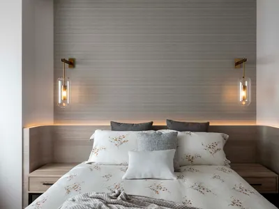 A minimalist bedroom with a bed adorned with floral-patterned bedding, grey pillows, and bedside lamps.