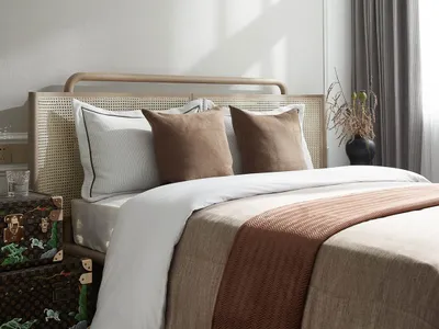 Minimalist bedroom with wooden bed frame, white bedding, and textured fabric accents.