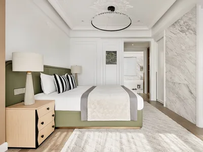 A modern bathroom featuring marble flooring, wooden cabinets, and a green upholstered bed.