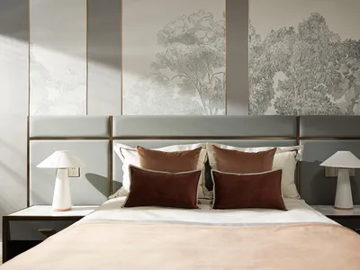 A minimalist bedroom with a bed, two nightstands with lamps, and a headboard with a nature-themed mural.