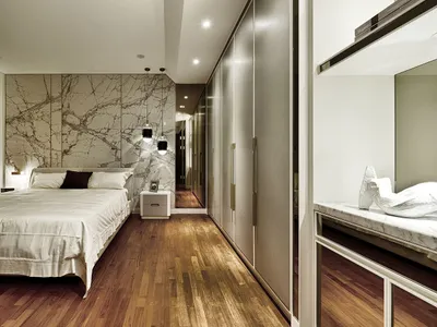 Modern minimalist bedroom with a marble accent wall and wooden flooring.