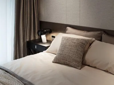 Minimalist bedroom with fabric-covered headboard and white bedding.