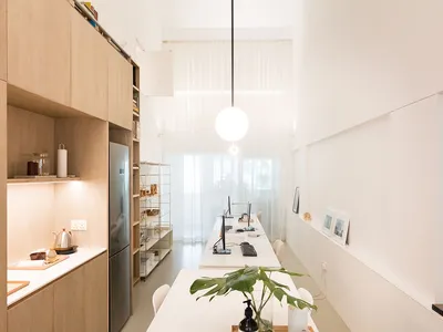 A minimalist residential kitchen with wooden cabinets and a long dining table.