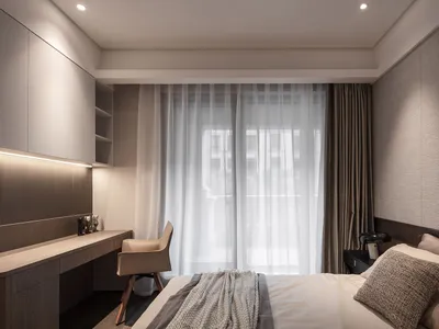 A modern bedroom with a bed, fabric blinds, and desk area