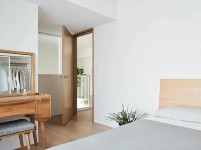 A minimalist bedroom featuring a bed with a wooden headboard and a glass closet door.