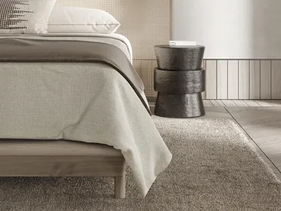 Minimalist bedroom with wooden bed frame, fabric bedding, and metallic side table