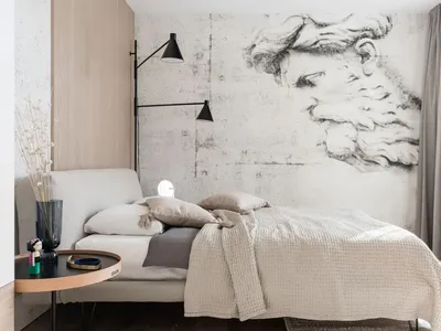 A minimalist bedroom with neutral tones featuring a bed, lamp, and artwork on the wall.