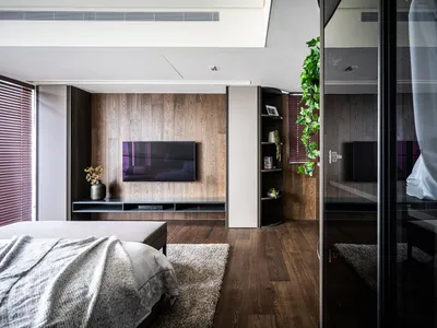 Spacious, minimalist bedroom featuring wood flooring and furniture.