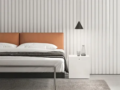 Minimalist bedroom featuring a metal frame bed with a taupe leather headboard, set against a textured wall and a nightstand w