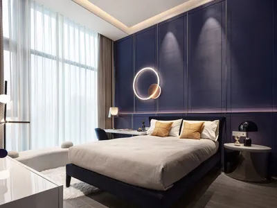 A modern bedroom featuring a fabric bed against a dark blue wall with a circular light fixture and white curtains.