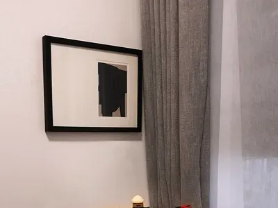 Modern home office featuring a wooden desk with colorful pencils and toys, a framed abstract artwork, and gray curtains.