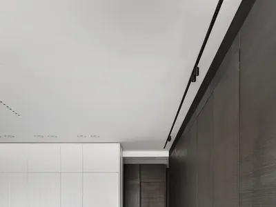 A modern minimalist kitchen with a concrete countertop, white and dark wood cabinets, and black stools.
