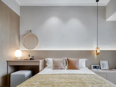 Modern minimalist bedroom featuring wooden walls, a neatly made bed with mixed-colored pillows, and a hanging lamp.