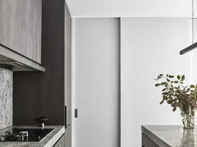 Modern minimalist kitchen with concrete countertops and wooden flooring.