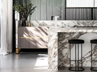 A modern minimalist kitchen with a marble countertop and black stools.