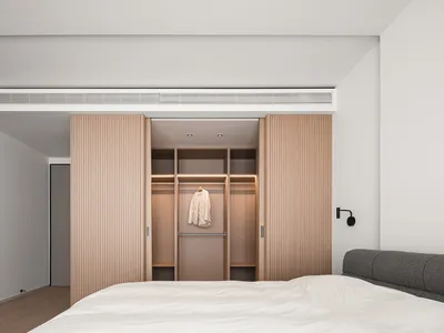 Modern minimalistic bedroom featuring wooden closet and bed.