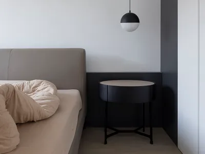 Minimalist bedroom with a bed, a bedside table, and a matte black pendant light hanging from the ceiling.