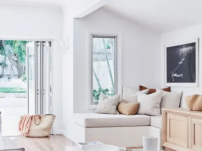 A minimalist living room with white walls, a wooden cabinet, and a concrete coffee table with books and a tray.