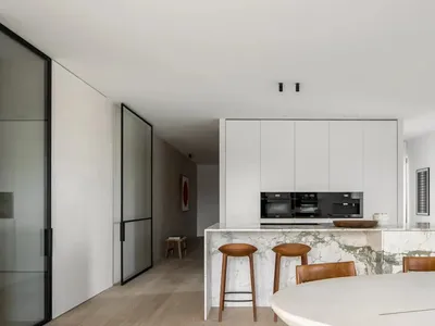 A modern kitchen featuring a marble island counter and white cabinets.
