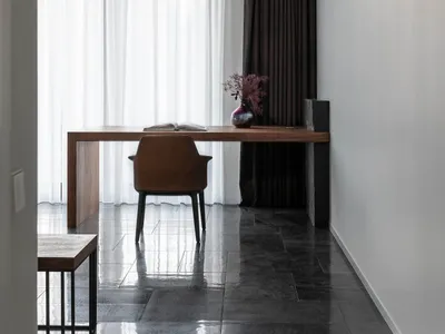 A minimalist home office with a wooden desk, glass panels, and a leather chair.
