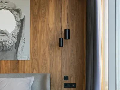 Modern minimalist bedroom featuring wooden walls, a grey upholstered bed, and a purple accent side table.