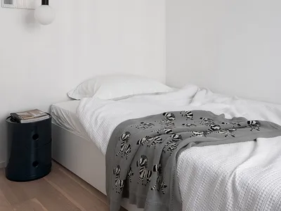 Minimalist bedroom featuring a bed with white bedding, a black accent lamp, and a wooden floor.
