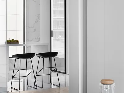 A modern kitchen and dining area with black stools and marble surfaces.