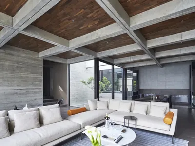 Modern industrial living room with concrete ceiling, white furniture, and open space.